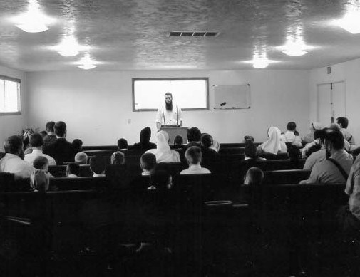 A speaker addressing a seated congregation