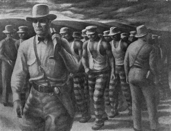 A guard walks in front of prisoners wearing striped clothing