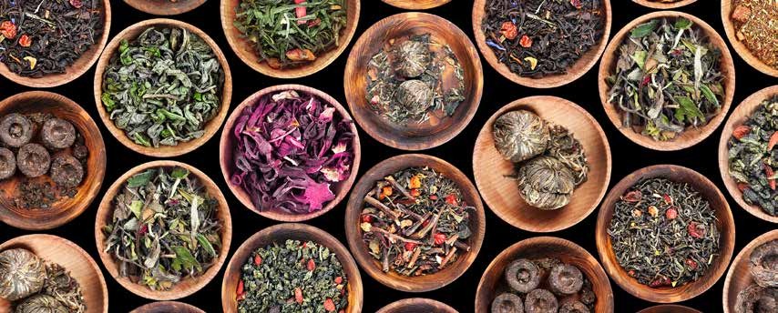 Assorted dried herbs and teas in round wooden bowls