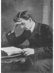 A man seated at a desk reading an open book