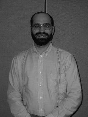 A bearded man wearing glasses and a collared shirt