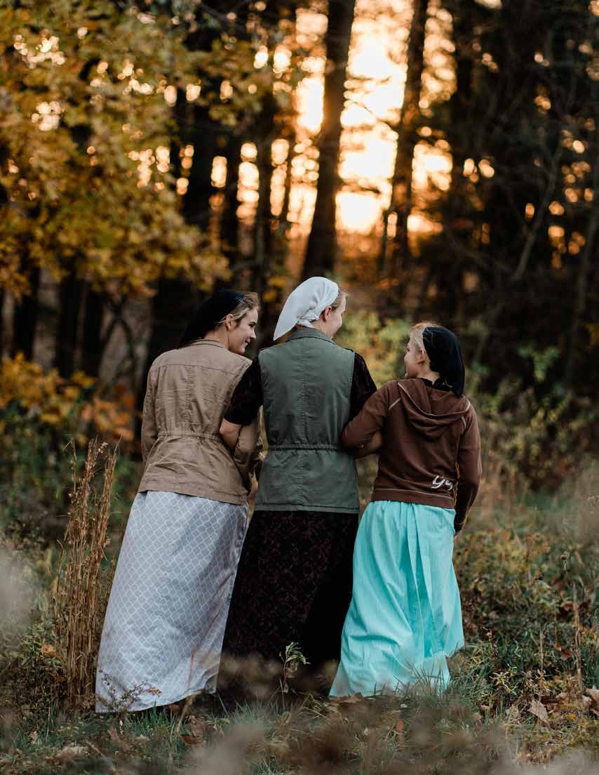 Three girls walking together through autumn woodland