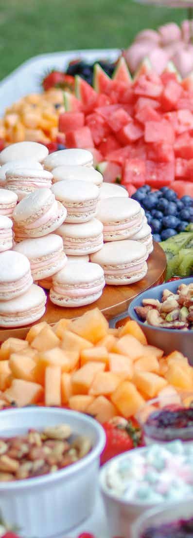 Macarons, sliced fruit, berries, and bowls of food at a buffet