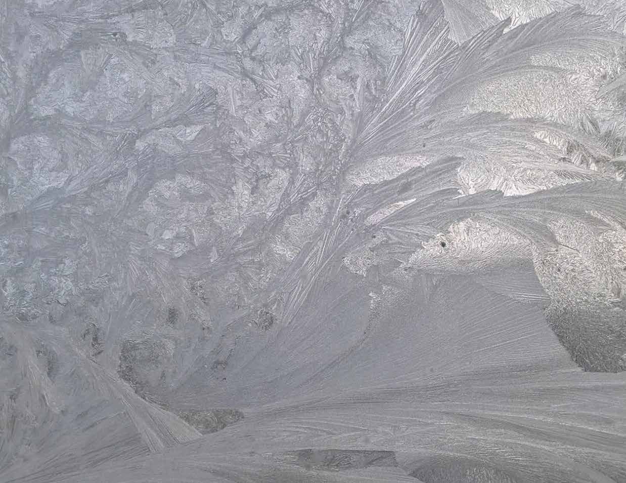 Frost crystals forming textured patterns on glass