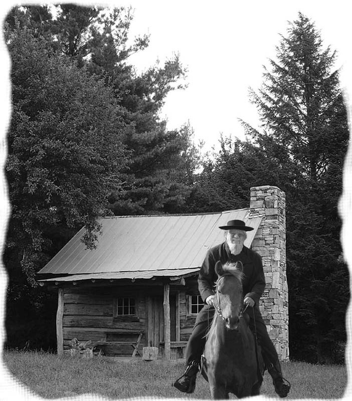 A man riding a horse in front of a log cabin