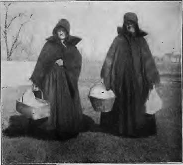 Two women carrying food containers outdoors