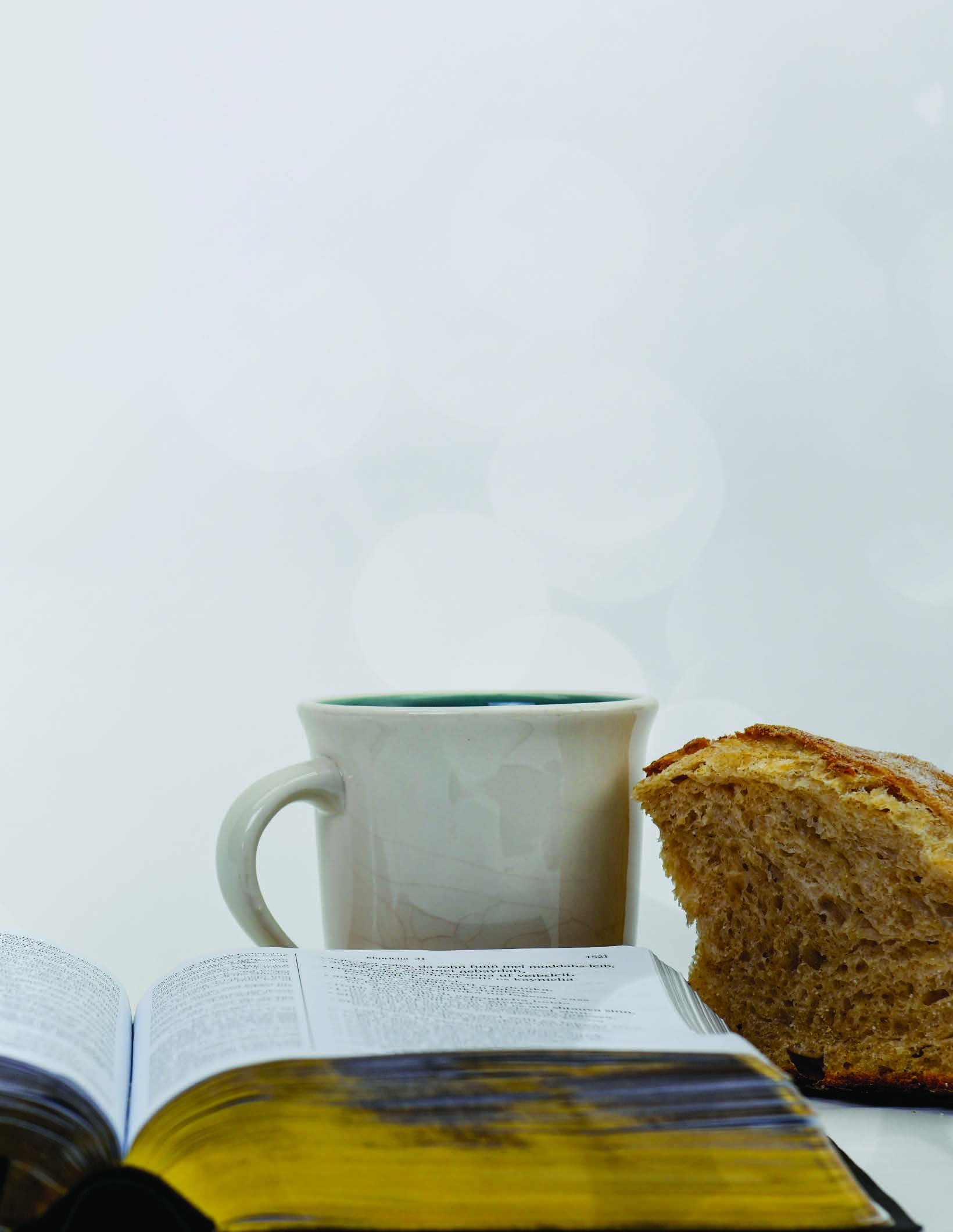 An open Bible with a mug and bread