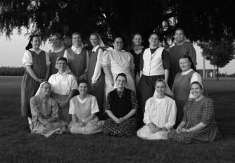 A group of women posed outdoors beneath trees.