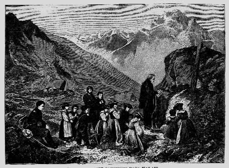 A group gathered in a mountain valley around a speaker
