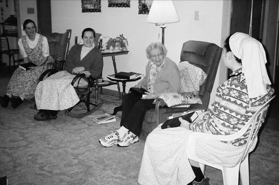 Young women visiting an older woman in a living room.
