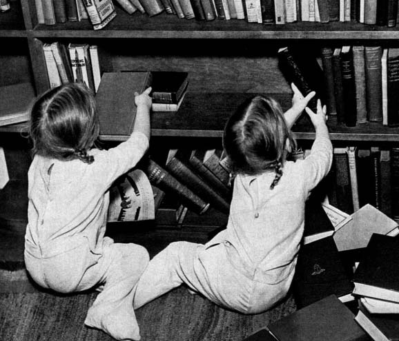 Two children taking books from a shelf