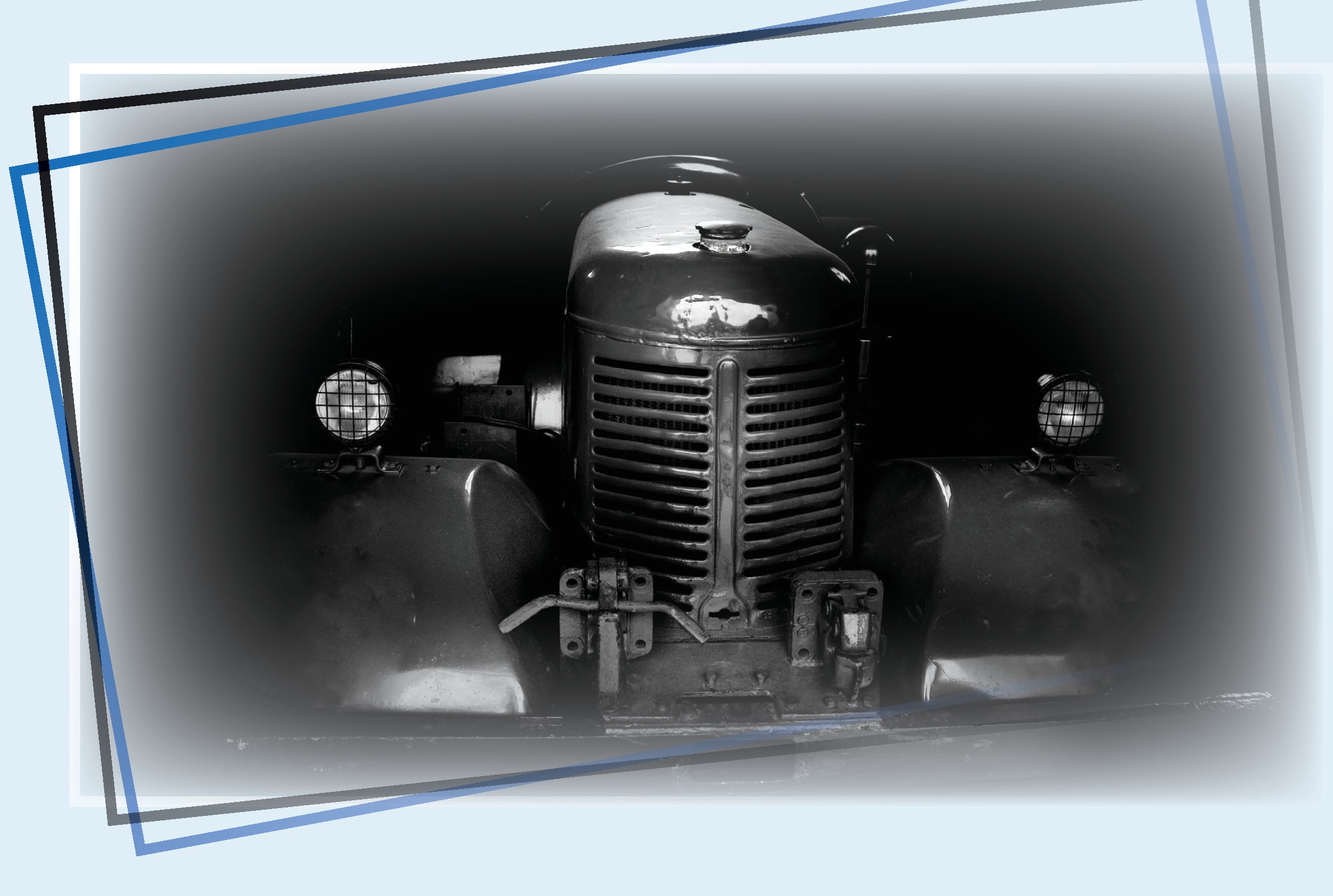 A vintage tractor seen head-on in a dark barn