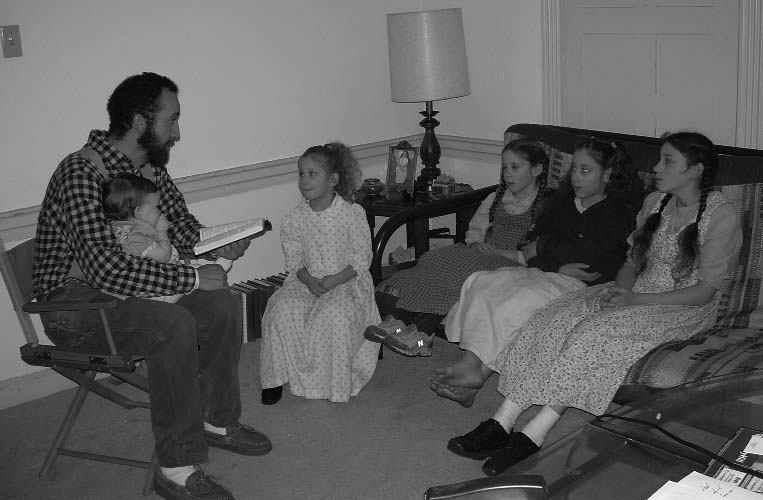 A man reading to children gathered around him