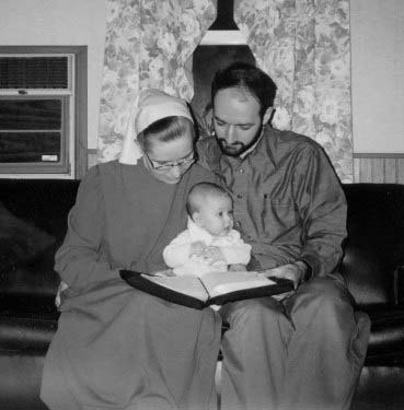 A couple with an infant reading an open book