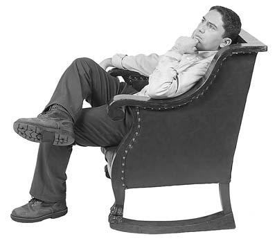 A man reclines in a chair, looking thoughtful.