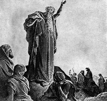 A robed man speaking to a gathered crowd