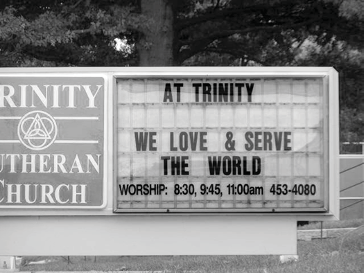 Roadside Trinity Lutheran Church sign saying We Love and Serve the World