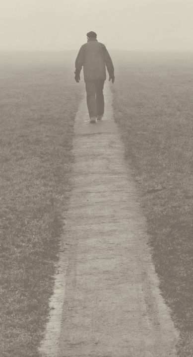A lone man walking along a foggy country road