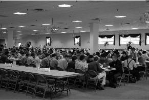 Youth Bible School participants meet around tables in a large hall.