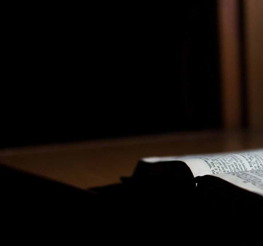 Open Bible in low light, left half of a two-page photograph