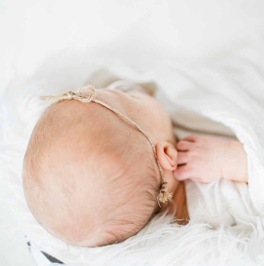 A sleeping newborn baby wearing a thin headband