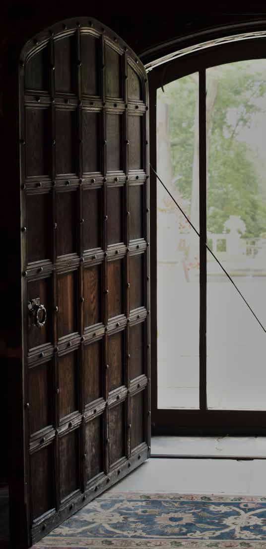 A large wooden door standing open toward a bright window