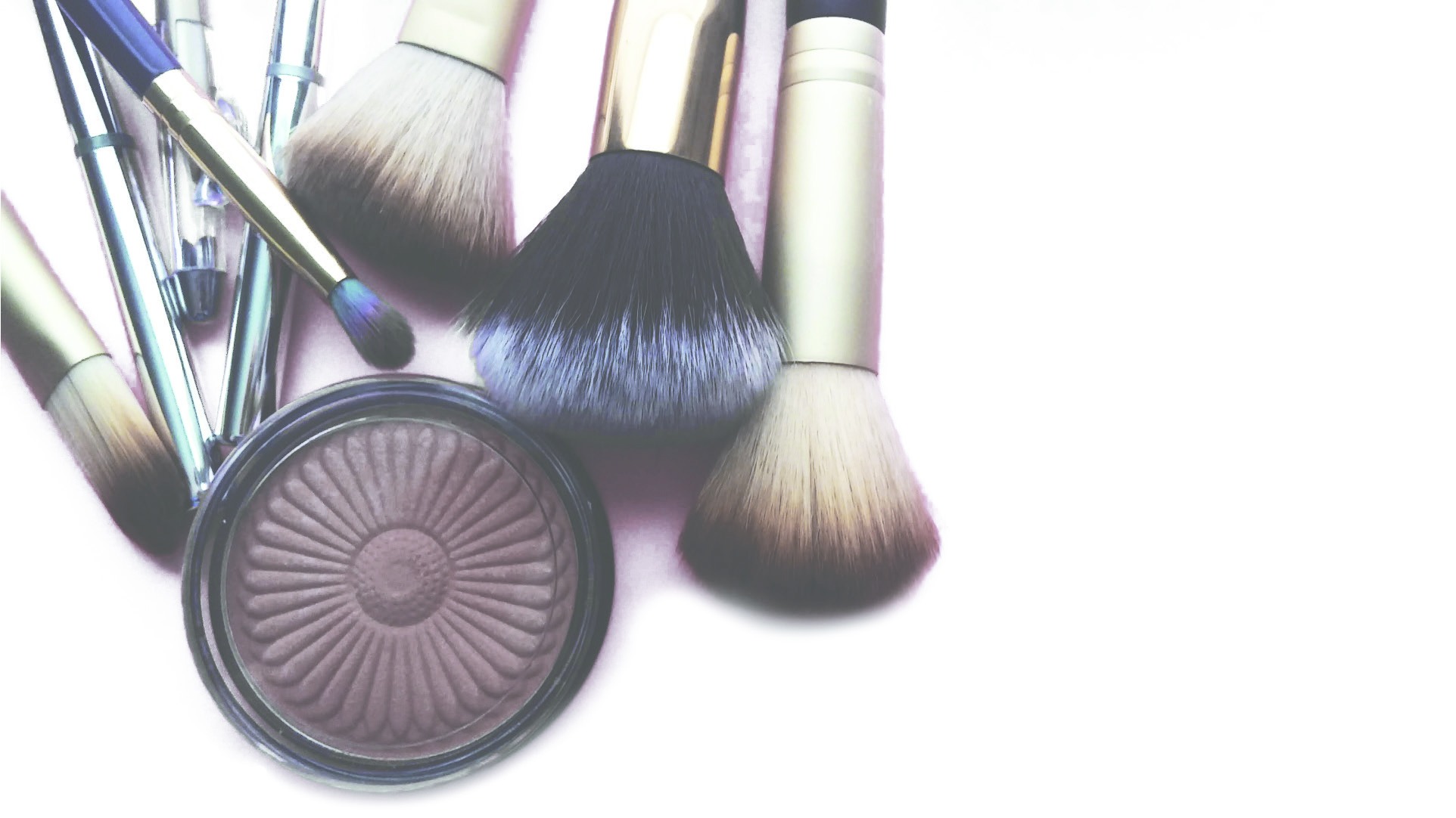 Makeup brushes arranged around a compact of pressed powder