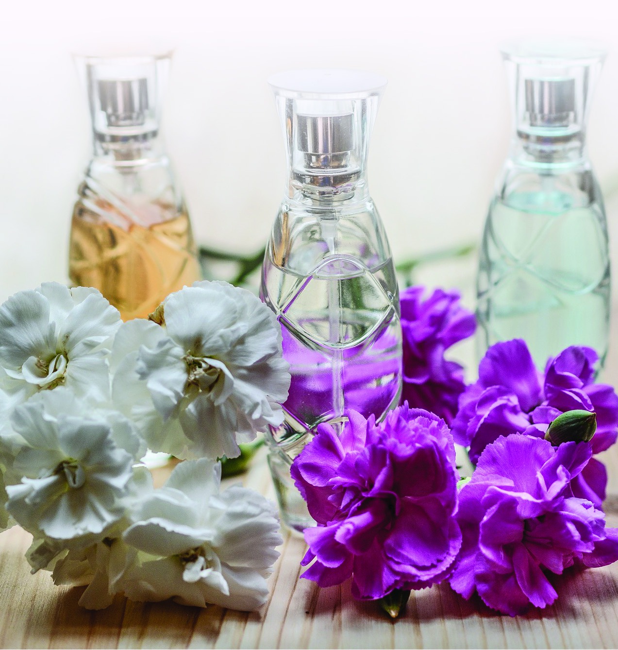 Perfume bottles arranged with white and purple flowers