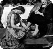 A person kneeling to wash another person’s feet.