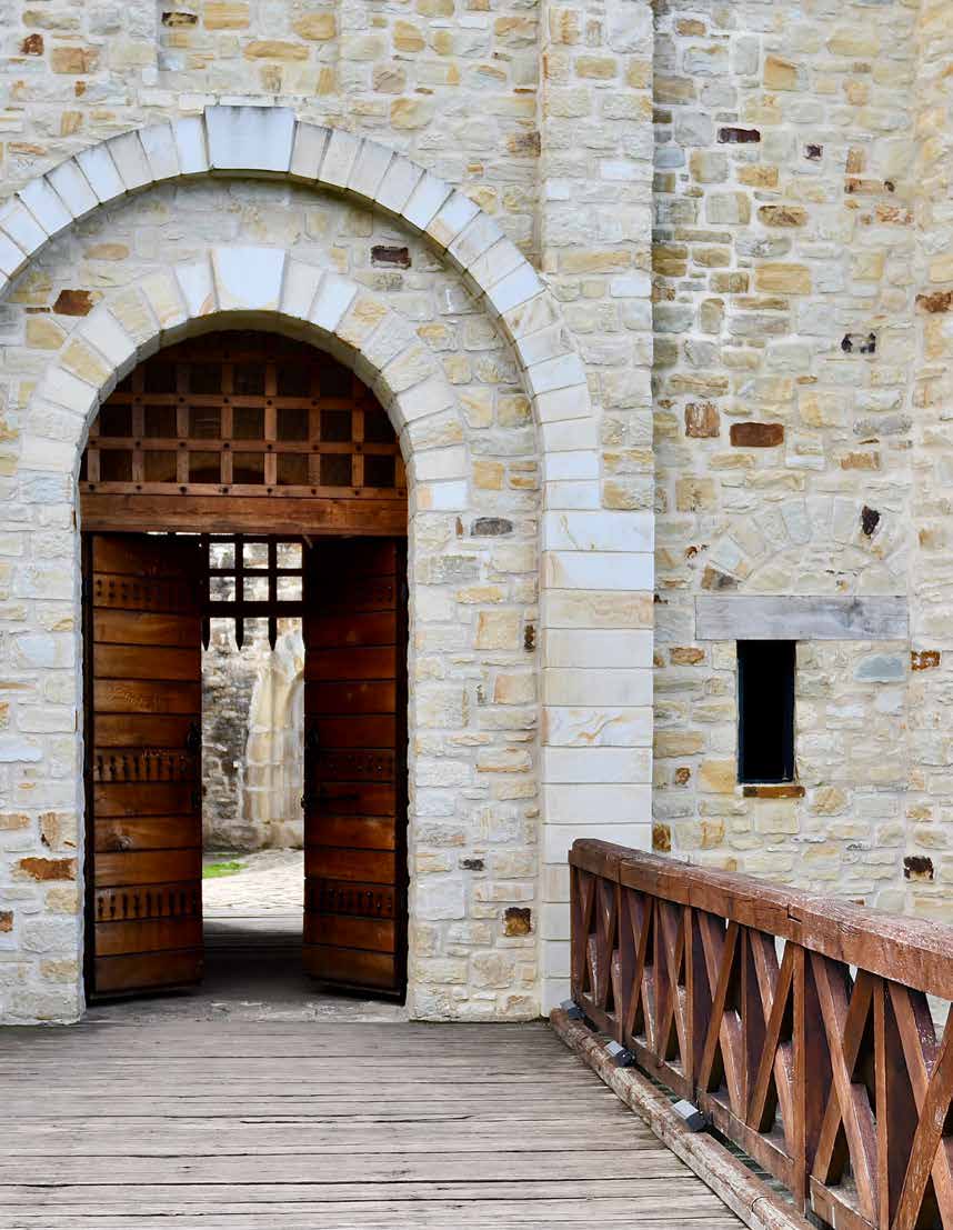 A wooden gate in a stone archway beside a wooden railing