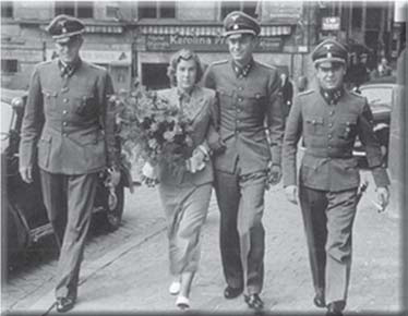 Traudl Junge walking beside three uniformed men