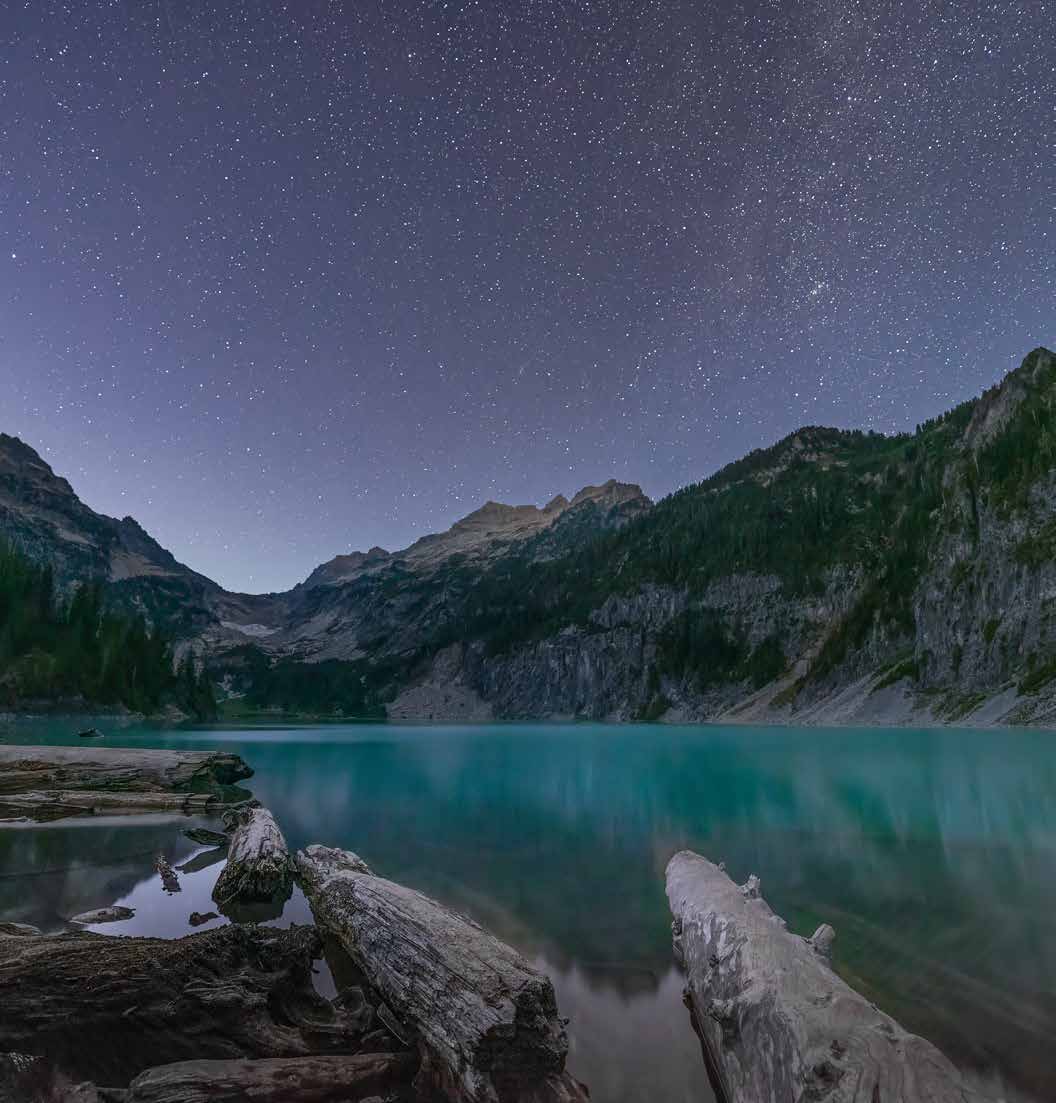 A star-filled night sky above a mountain lake