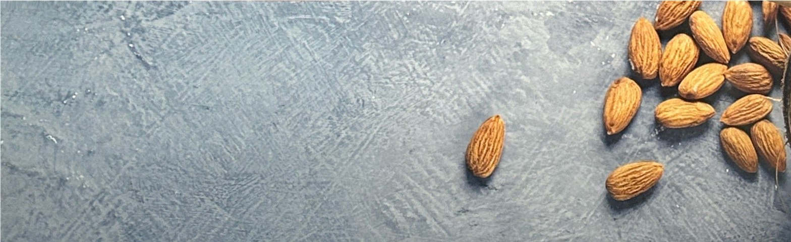 Almonds scattered on a textured gray surface.