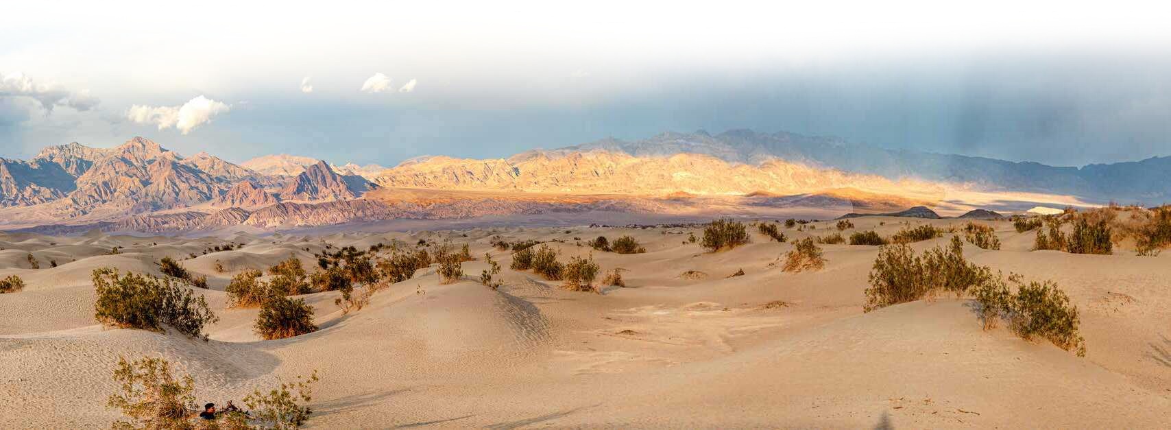 A broad desert valley beneath layered mountains and clouds