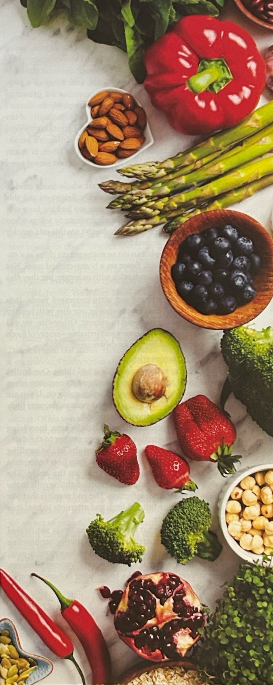 Fresh vegetables, fruit, nuts, and legumes arranged on a light surface.