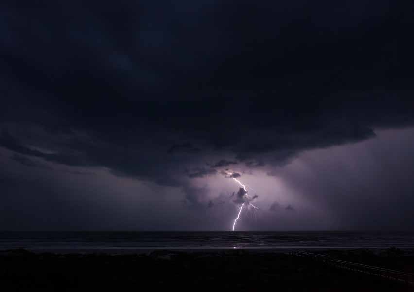 Lightning beneath dark storm clouds over a field