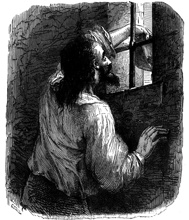 A man looking through an opening in a stone prison wall
