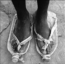Feet wearing worn sandals on dirt