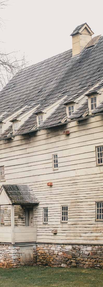 A historic white meetinghouse with a steep shingled roof