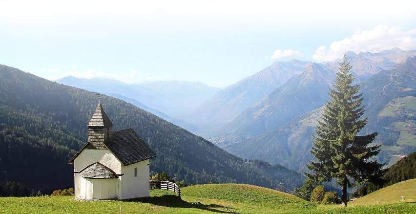 A small white church in a mountain valley