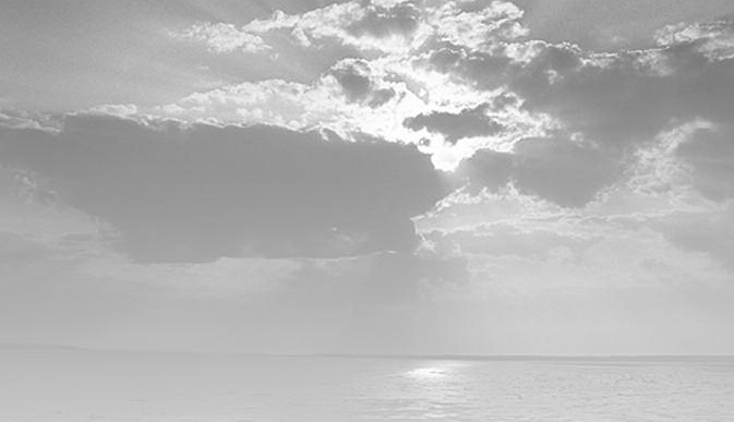 Sunlight breaks through clouds above the sea.