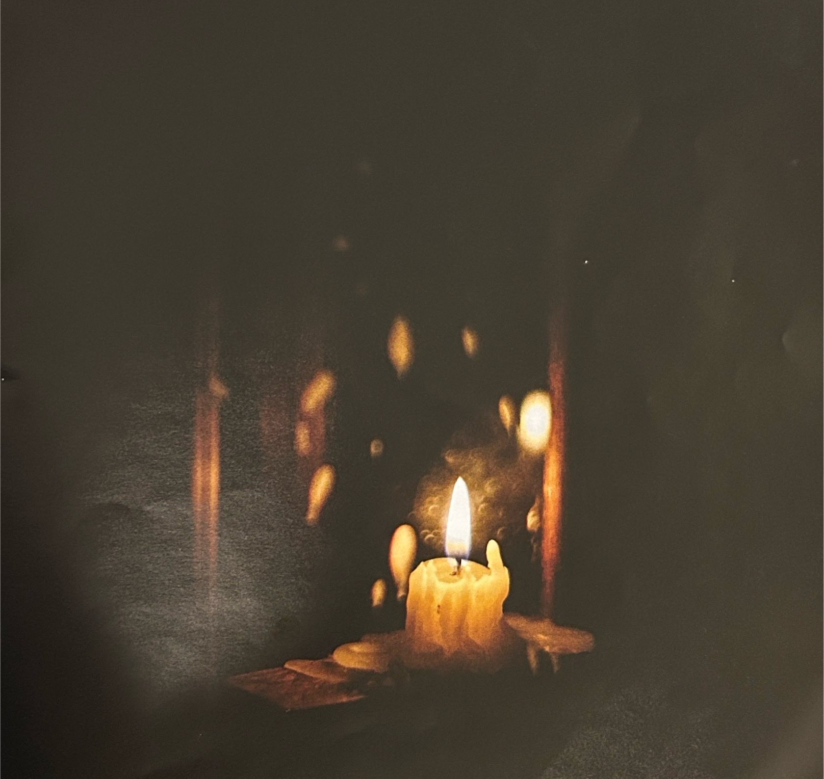 A lit candle in a dark setting.