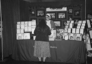 Visitors stand at a Tape Ministry booth displaying recordings and literature.