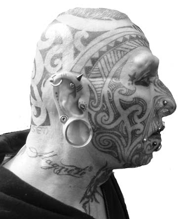 Profile of a man with facial tattoos and piercings