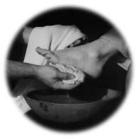 Hands wash a foot over a basin.