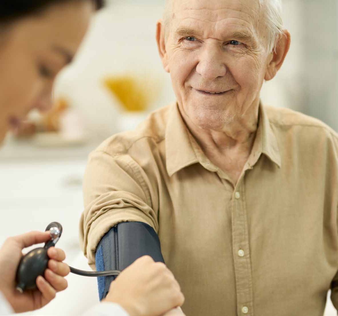 A clinician checks an older man’s blood pressure