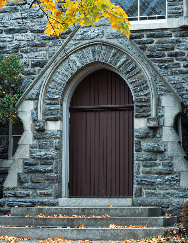 A church doorway framed by stonework and autumn leaves.