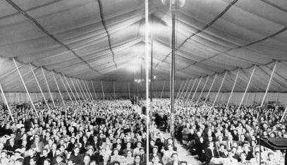 Crowd seen across the interior of a revival tent