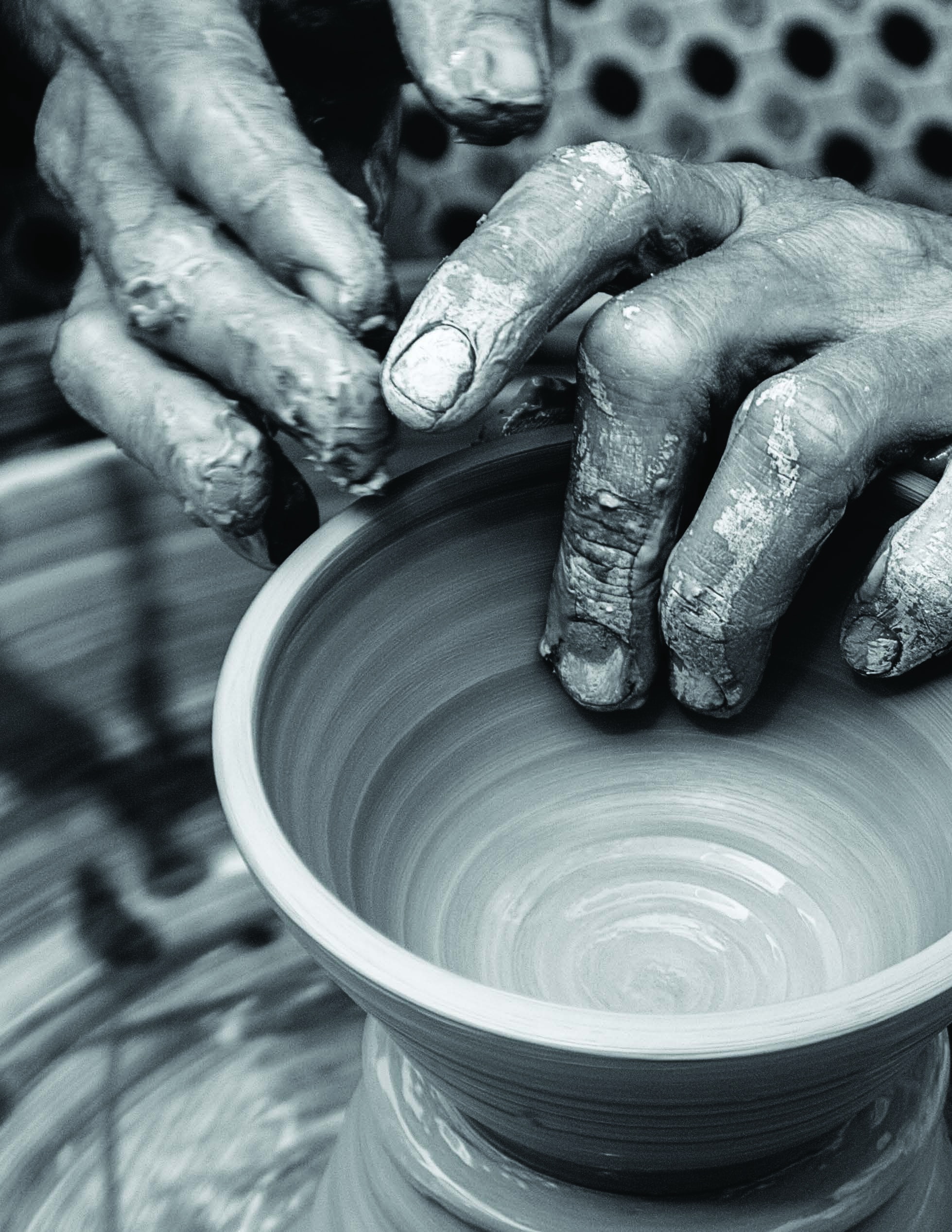 Hands shaping a clay pot on a potter’s wheel