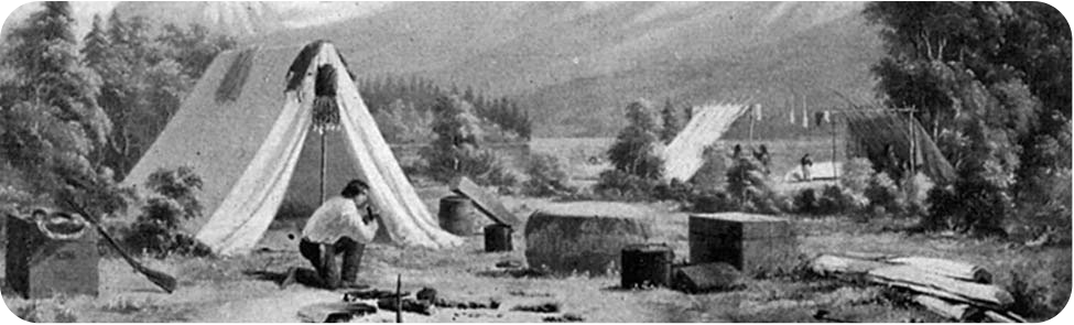 A man sitting beside a tent in a wooded camp